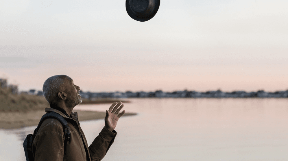 Woman standing outdoors with arms raised at sunset, feeling joyful and free
